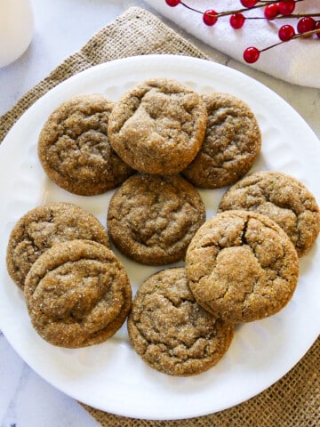 plate of ginger snaps with red holly in the background.