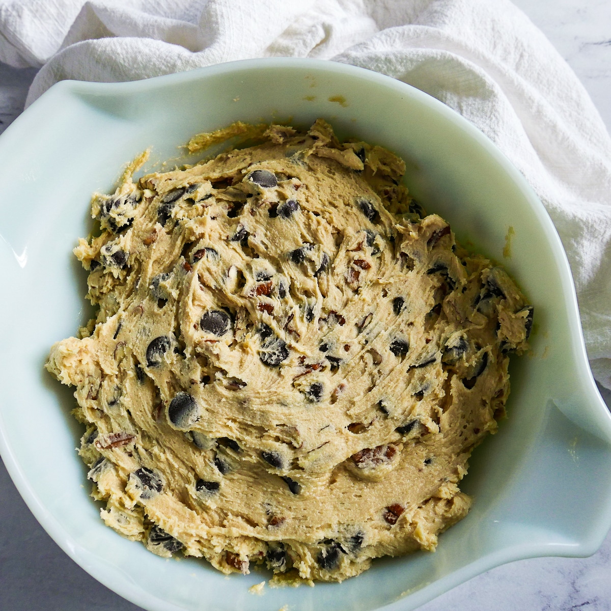 chocolate-chips-and-pecans-in-cookie-dough.jpg chocolate chips and pecans mixed into cookie dough.