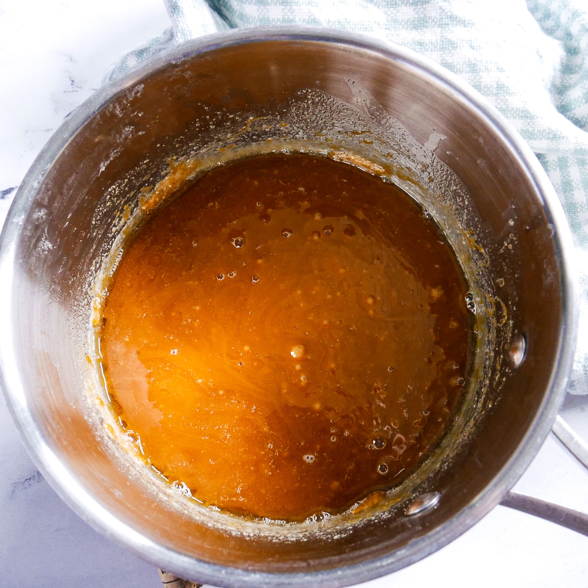 butter-and-cream-added-to-sugar.jpg melted sugar mixed with butter and heavy cream in a saucepan.
