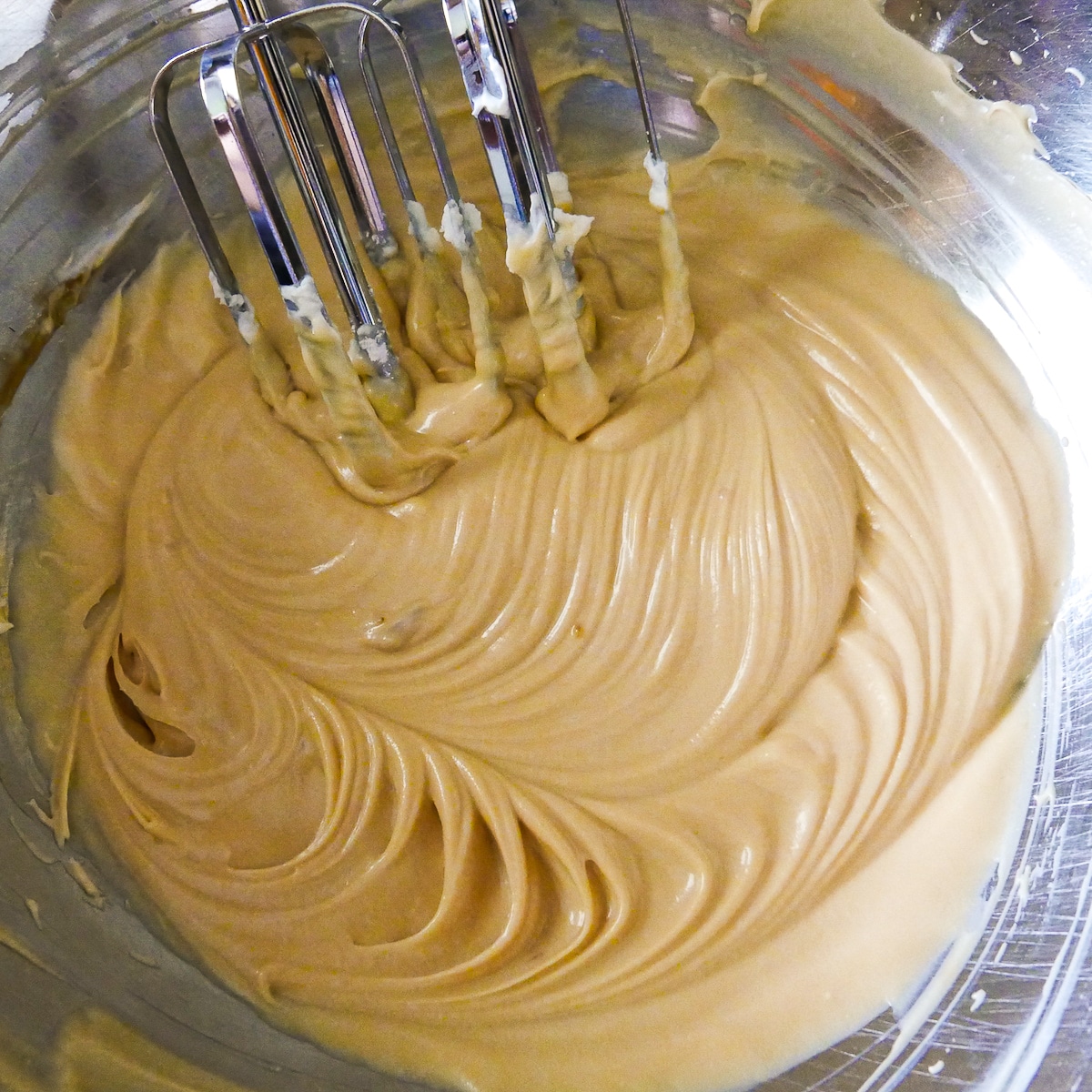 caramel sauce and powdered sugar added to cream cheese in bowl.