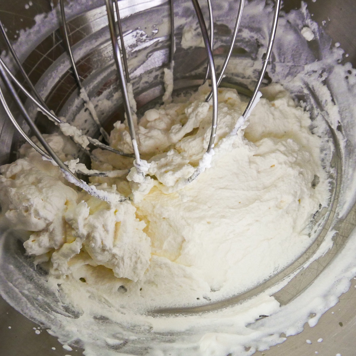 whipped cream being mixed in a stand mixer.