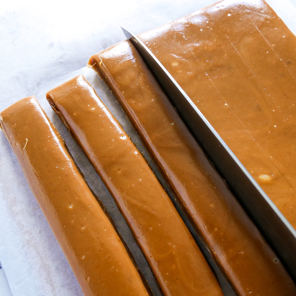 knife slicing caramel on parchment paper.