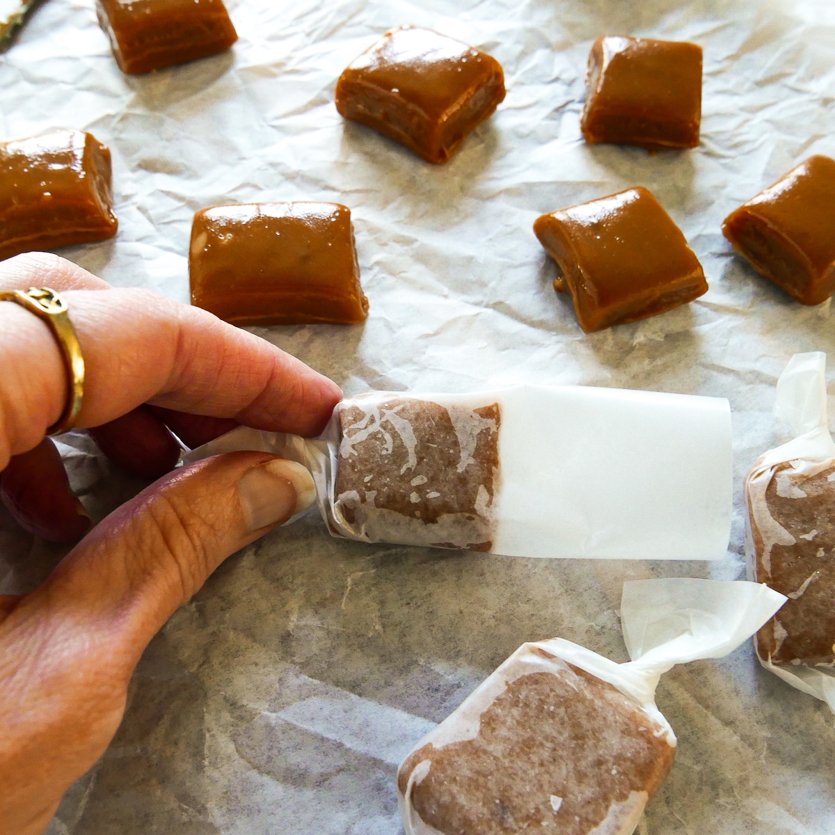 hand wrapping caramel in wax paper.