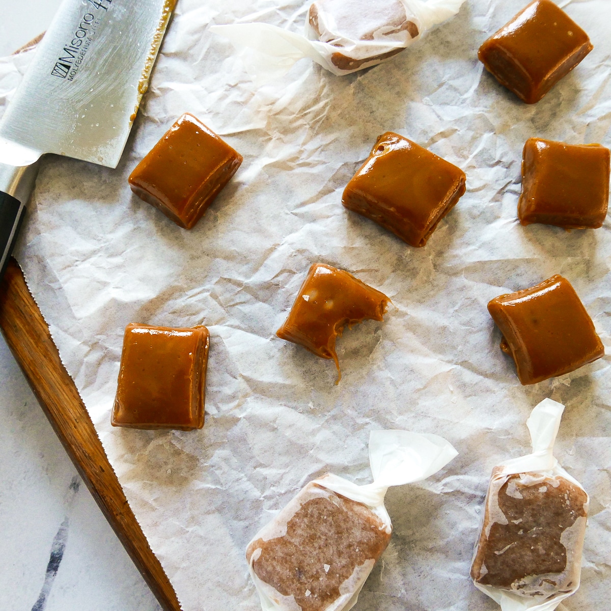 salted caramels aranged on parchment paper with a knife.