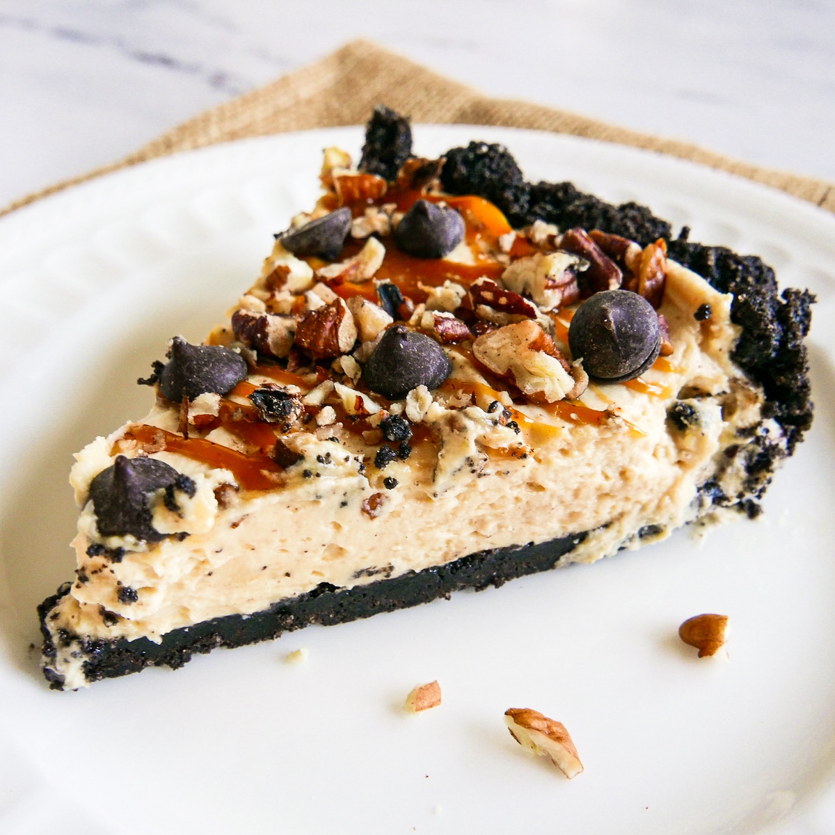 slice-of-pie.jpg slice of pecan turtle pie on a white plate with chopped pecans.