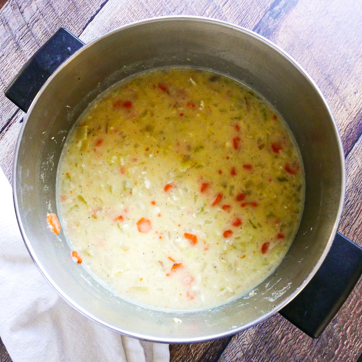 potato soup in large pot after having been mashed with potato masher.