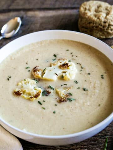 bowl of roasted cauliflower soup with two spoons.