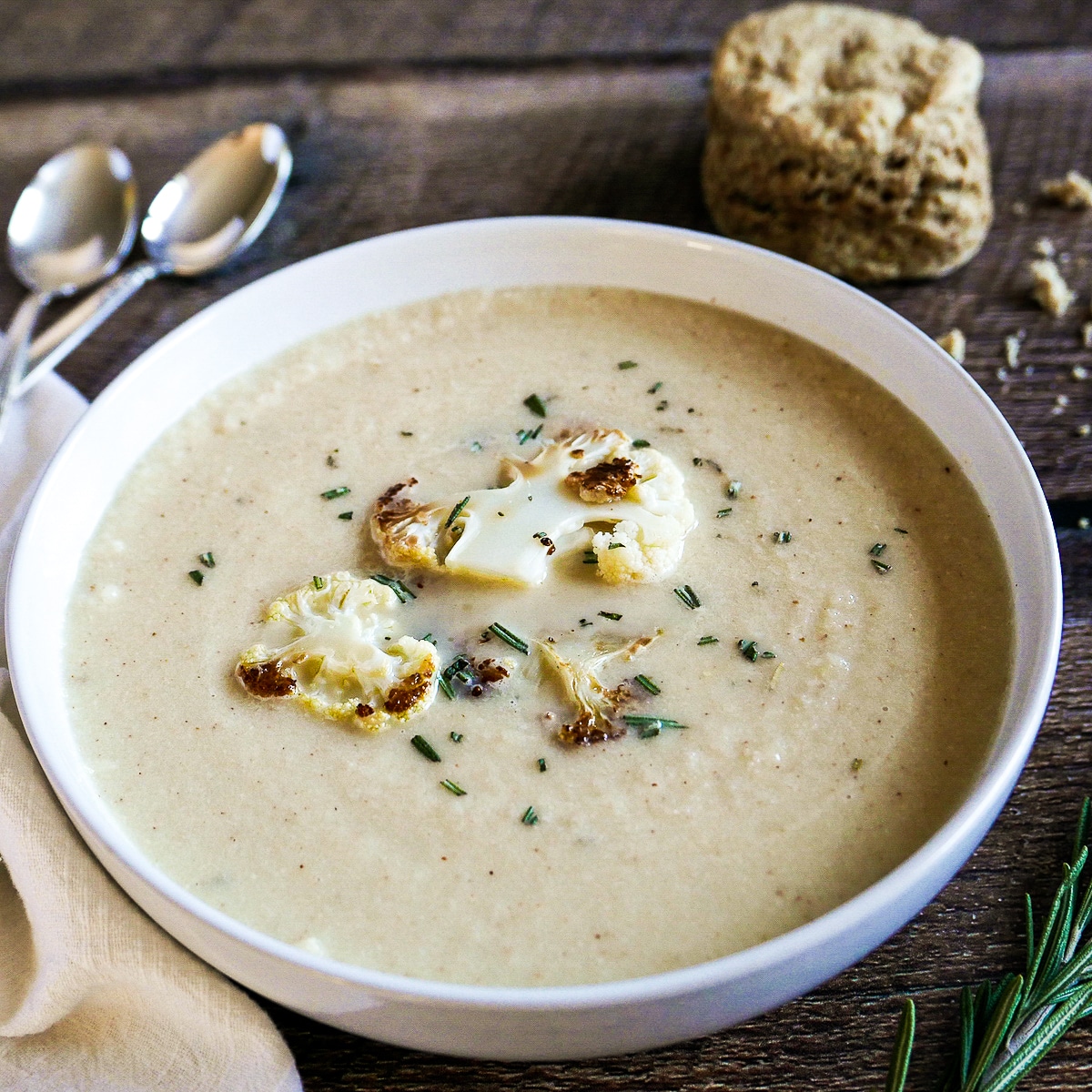 bowl of roasted cauliflower soup with two spoons.