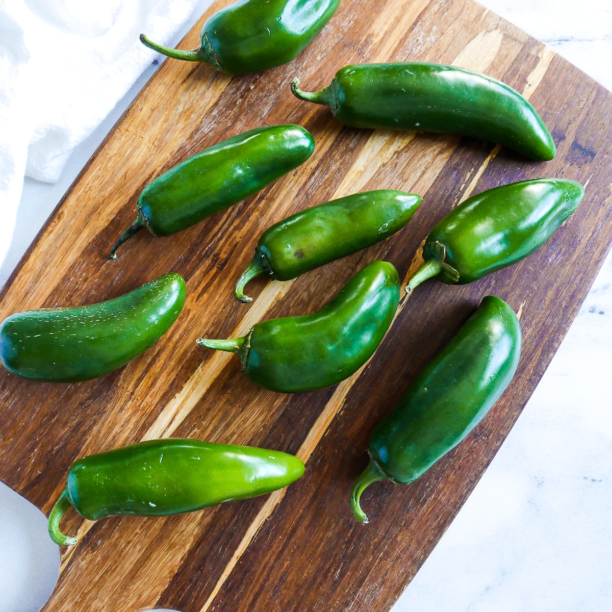 jalapenos-on-cutting-board.jpg jalapeno peppers arranged on a cutting board.