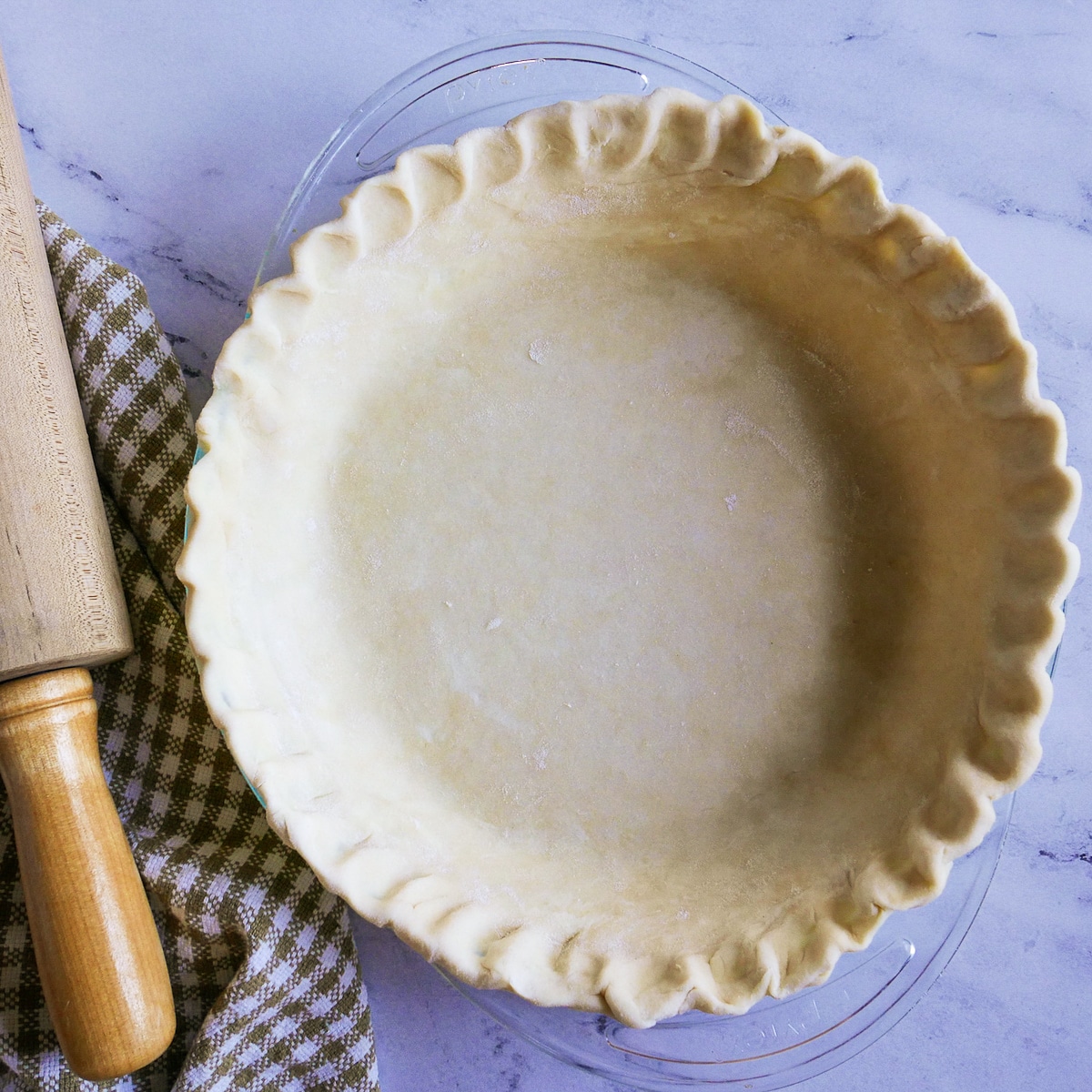 pie dough pressed into a pie pan with a rolling pin on the side.