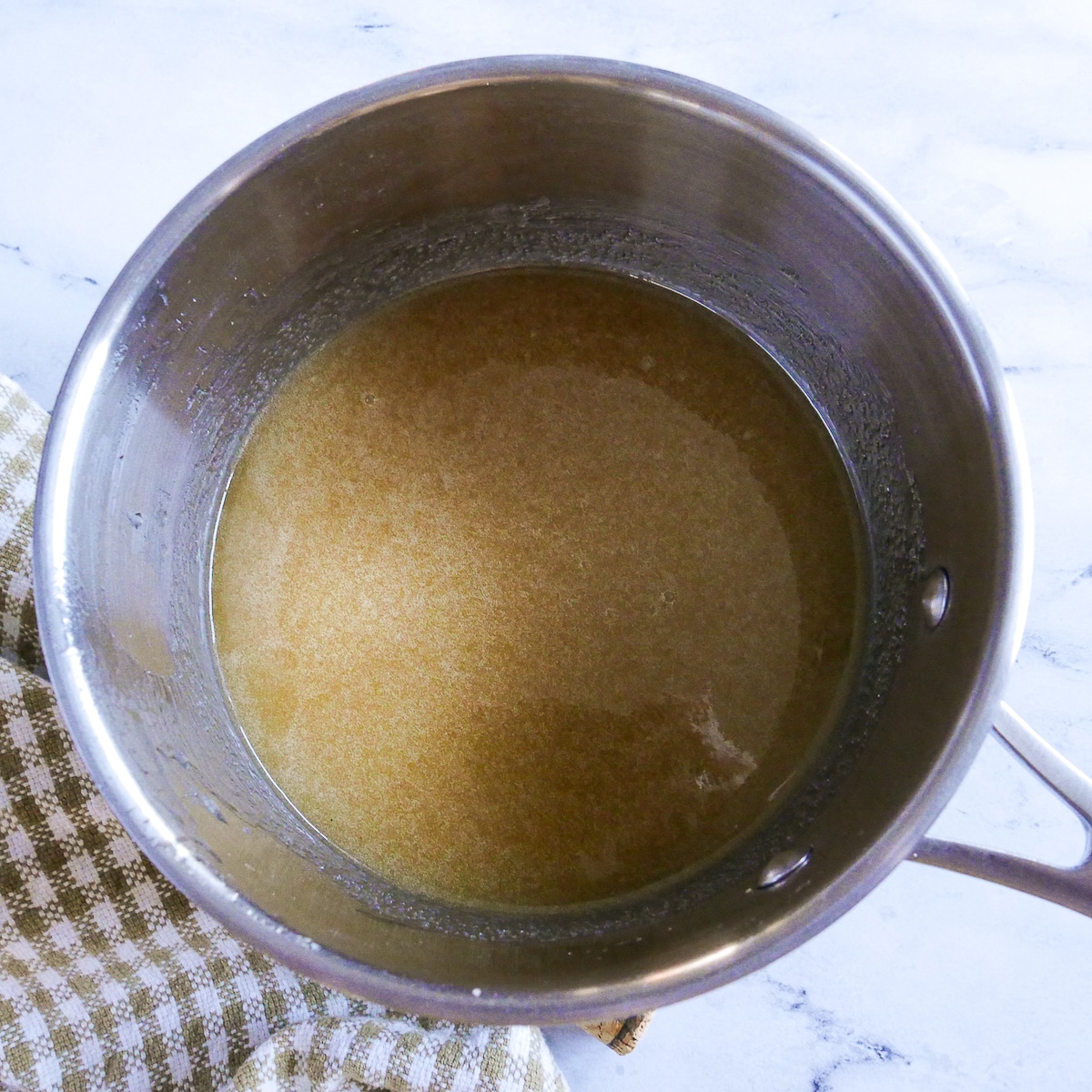 corn syrup, butter, and brown sugar cooking in a saucepan.