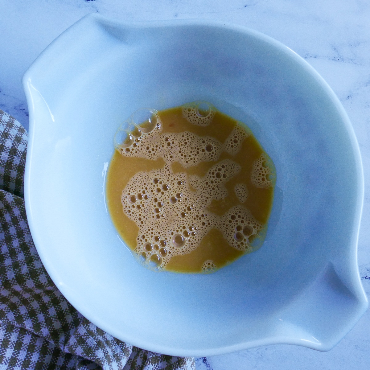 beat eggs and vanilla extract combined in a mixing bowl.