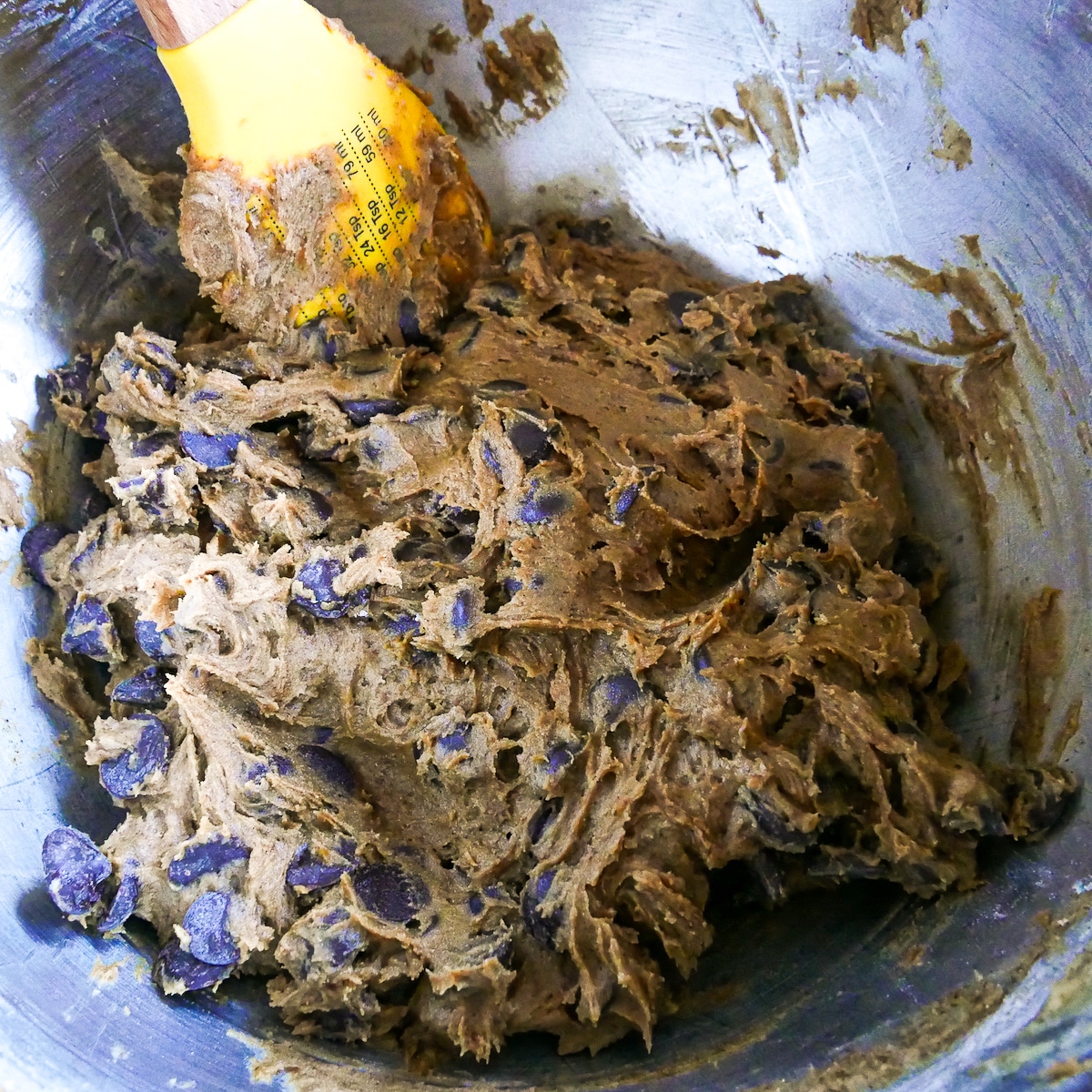 rubber spatula mixing chocolate chips into cookie dough.