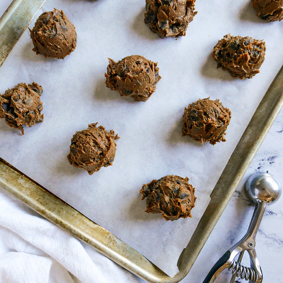 cookie dough scooped onto a parchment lined baking sheet.