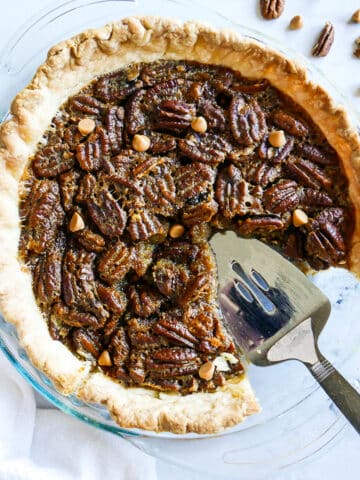 pie server resting in a pan of pecan pie.