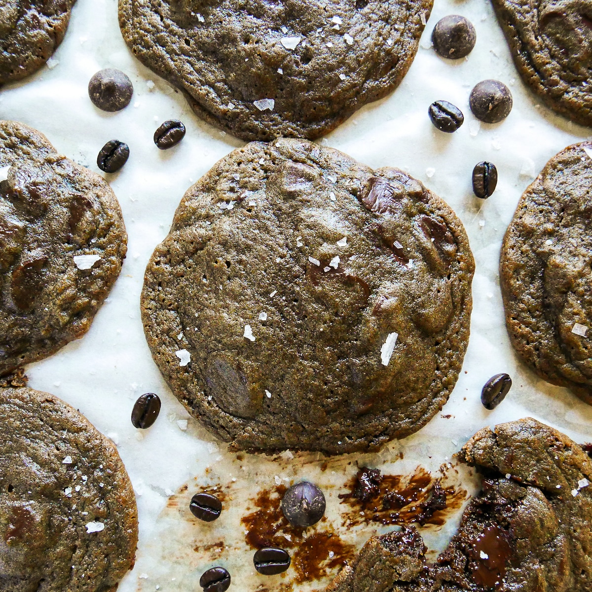 chewy espresso cookies arranged on parchment with coffee beans.