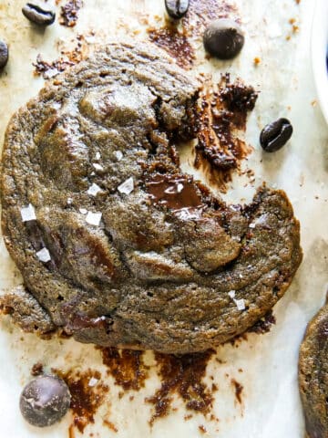 chocolate coffee cookie on parchment paper with a bite missing.