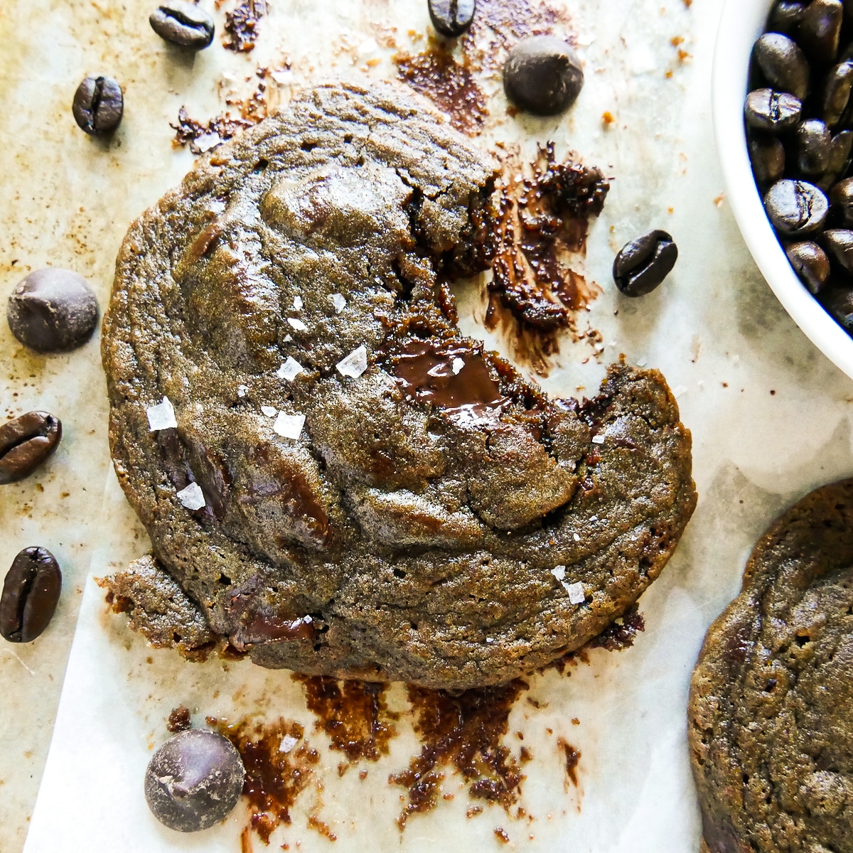 espresso chocolate chip cookie on parchment paper with a bite missing.