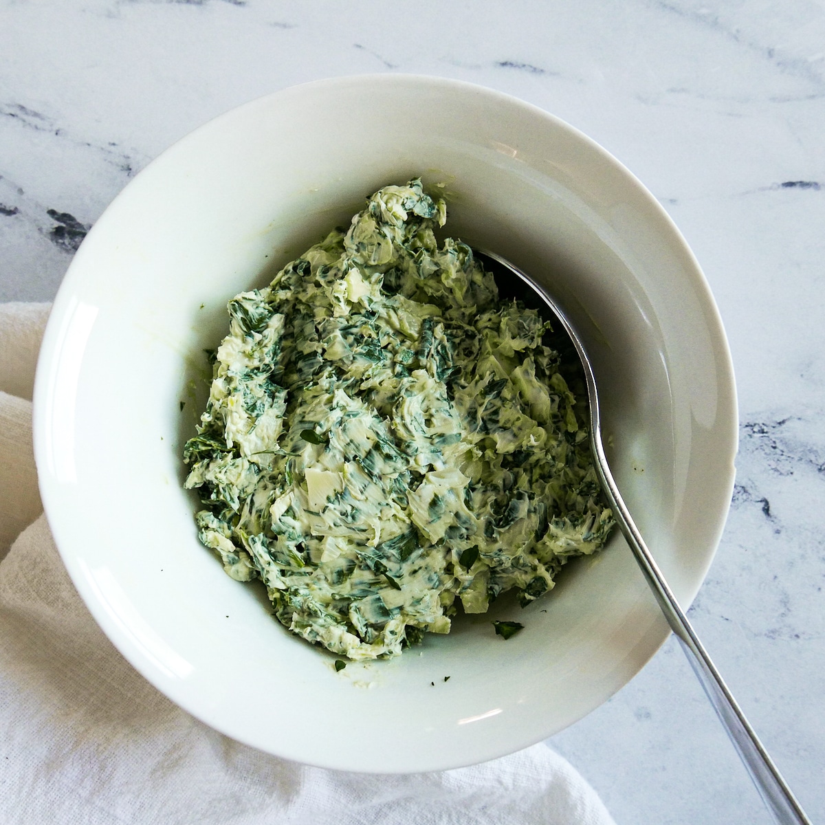 spinach filling mixed in a bowl with a spoon.