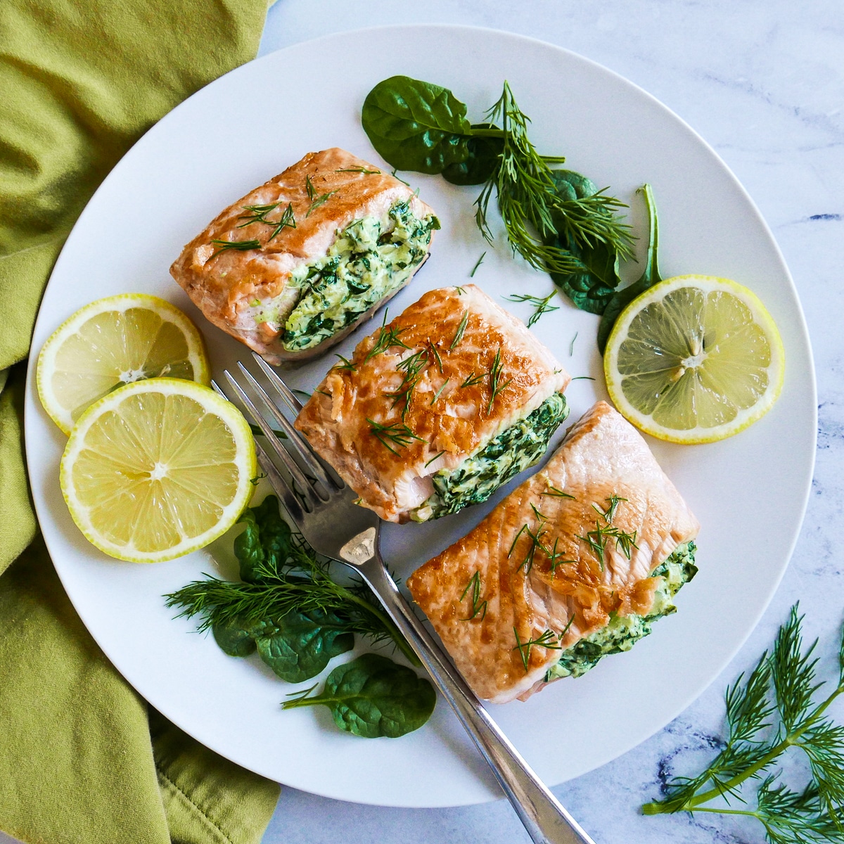 plate of three pieces of salmon with a fork and lemon slices.