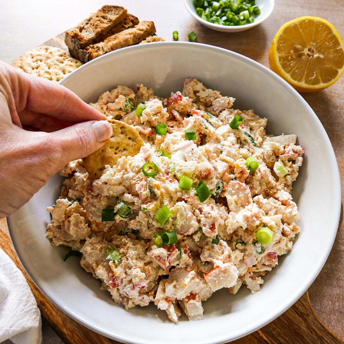 hand dipping cracker into a bowl of dip.