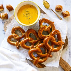 bowl of pretzel cheese dip with soft pretzels on a cutting board.