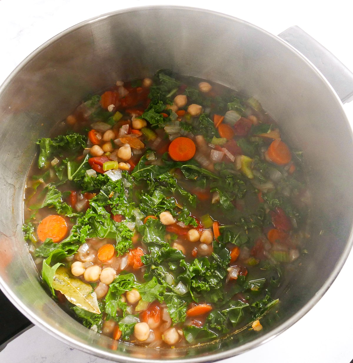 spinach added to soup mixture in a pot.