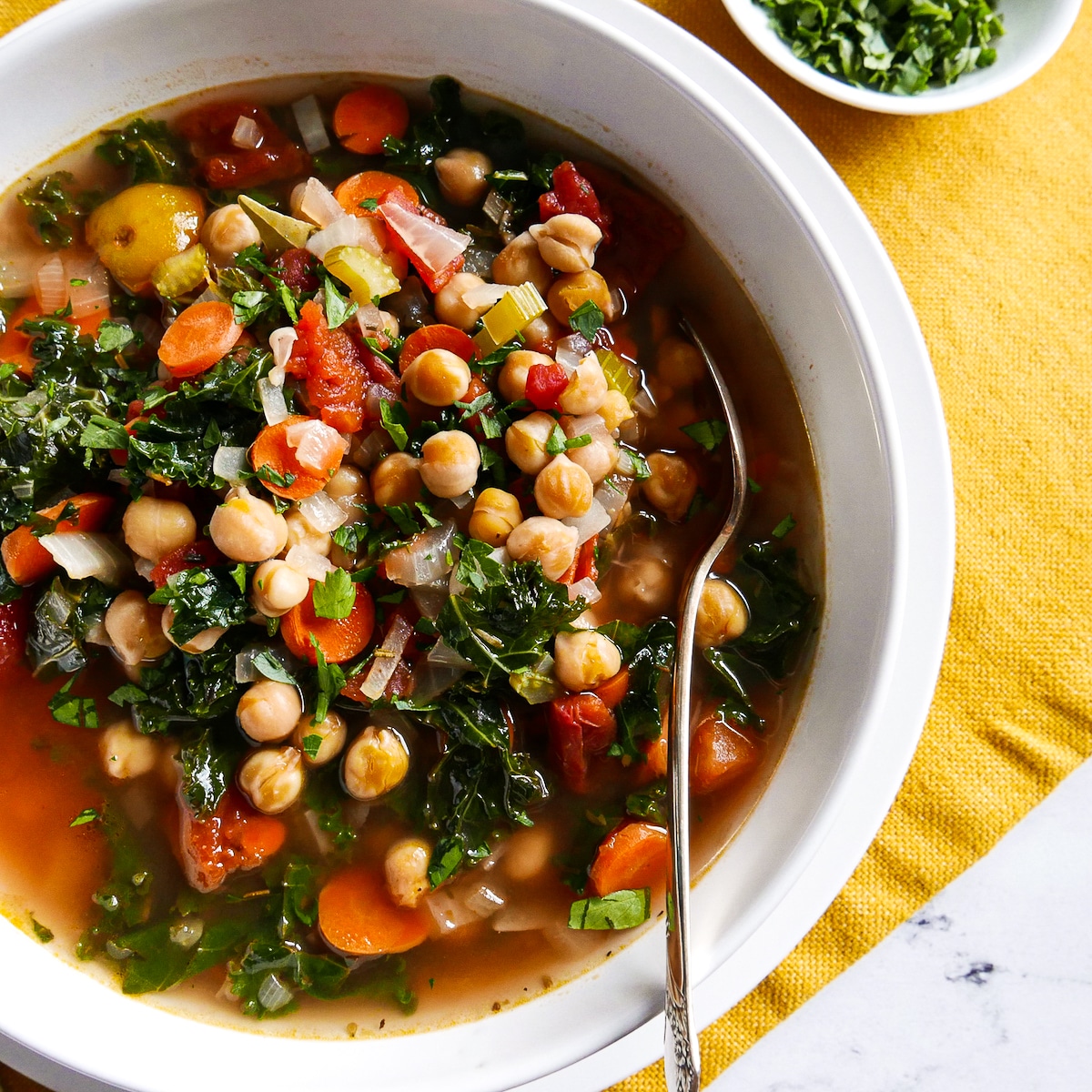 bowl of garbanzo bean soup with a spoon on a placemat.