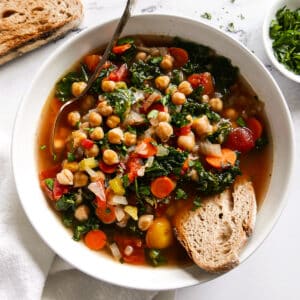 bowl of chickpea soup with a spoon and piece of bread.