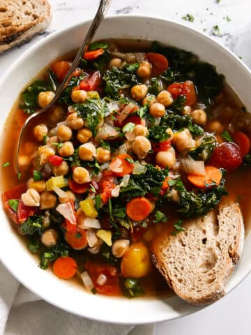 bowl of chickpea soup with a spoon and piece of bread.