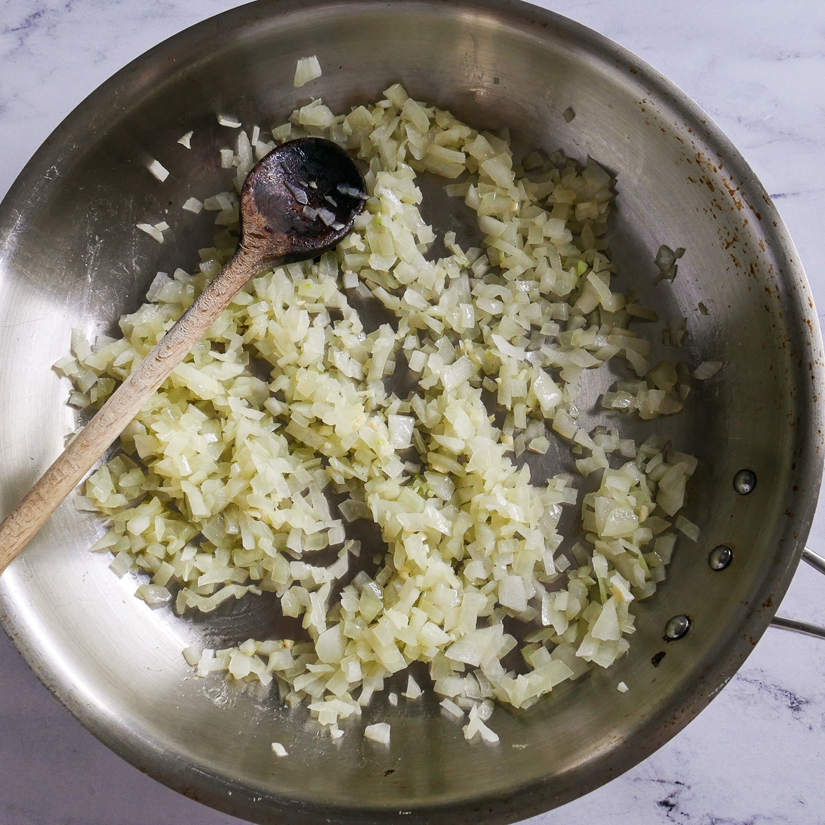 onion and garlic cooking in a saucepan with a wooden spoon.