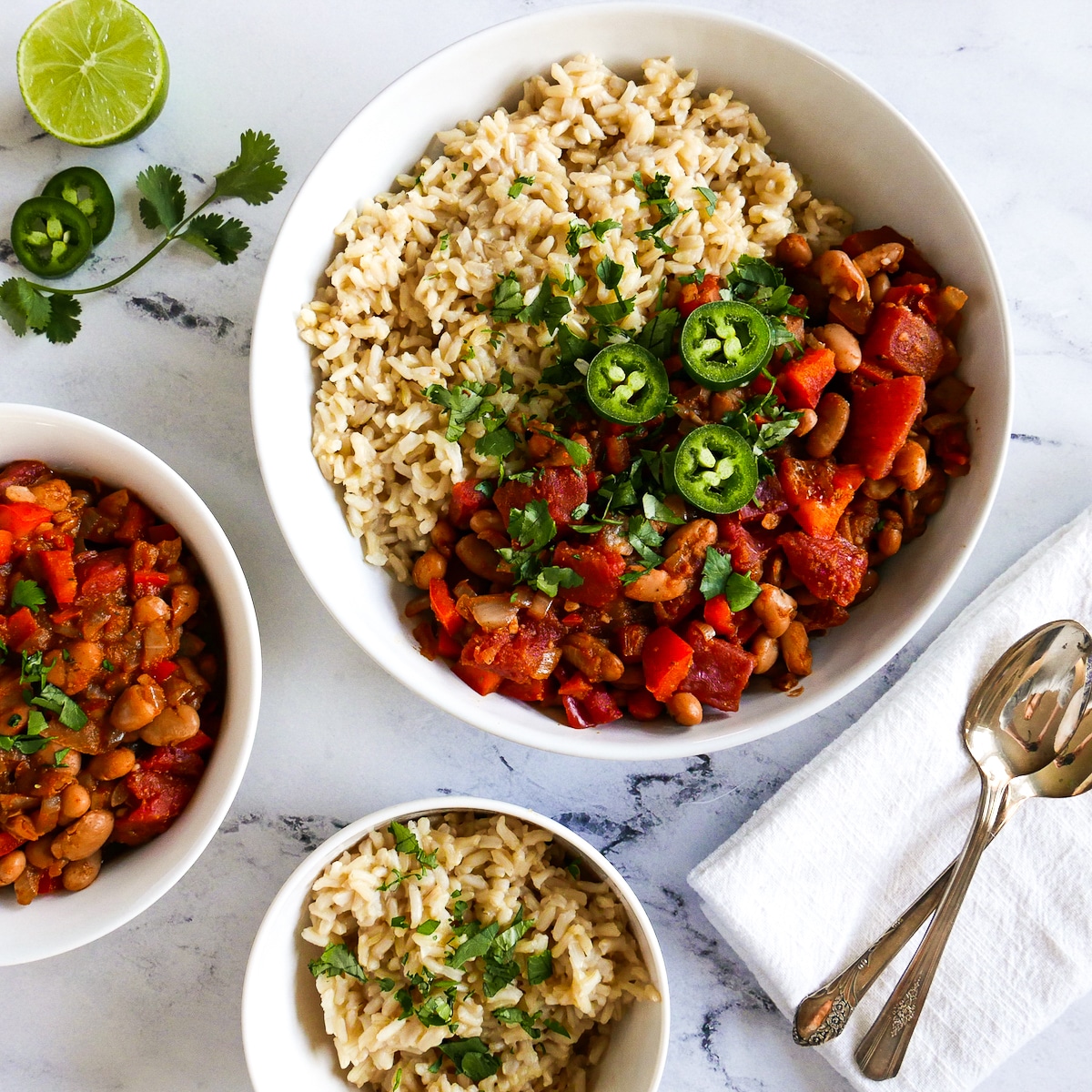 pinto-beans-and-rice.jpg bowl of pinto beans and rice with two spoons and a napkin.