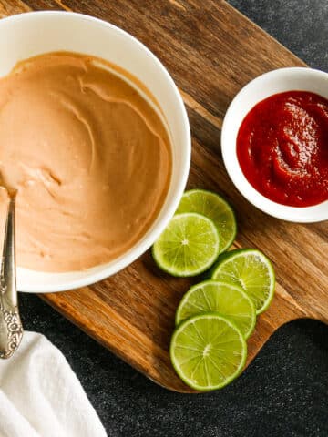 bowl of homemade spicy aioli with fresh limes on a cutting board.
