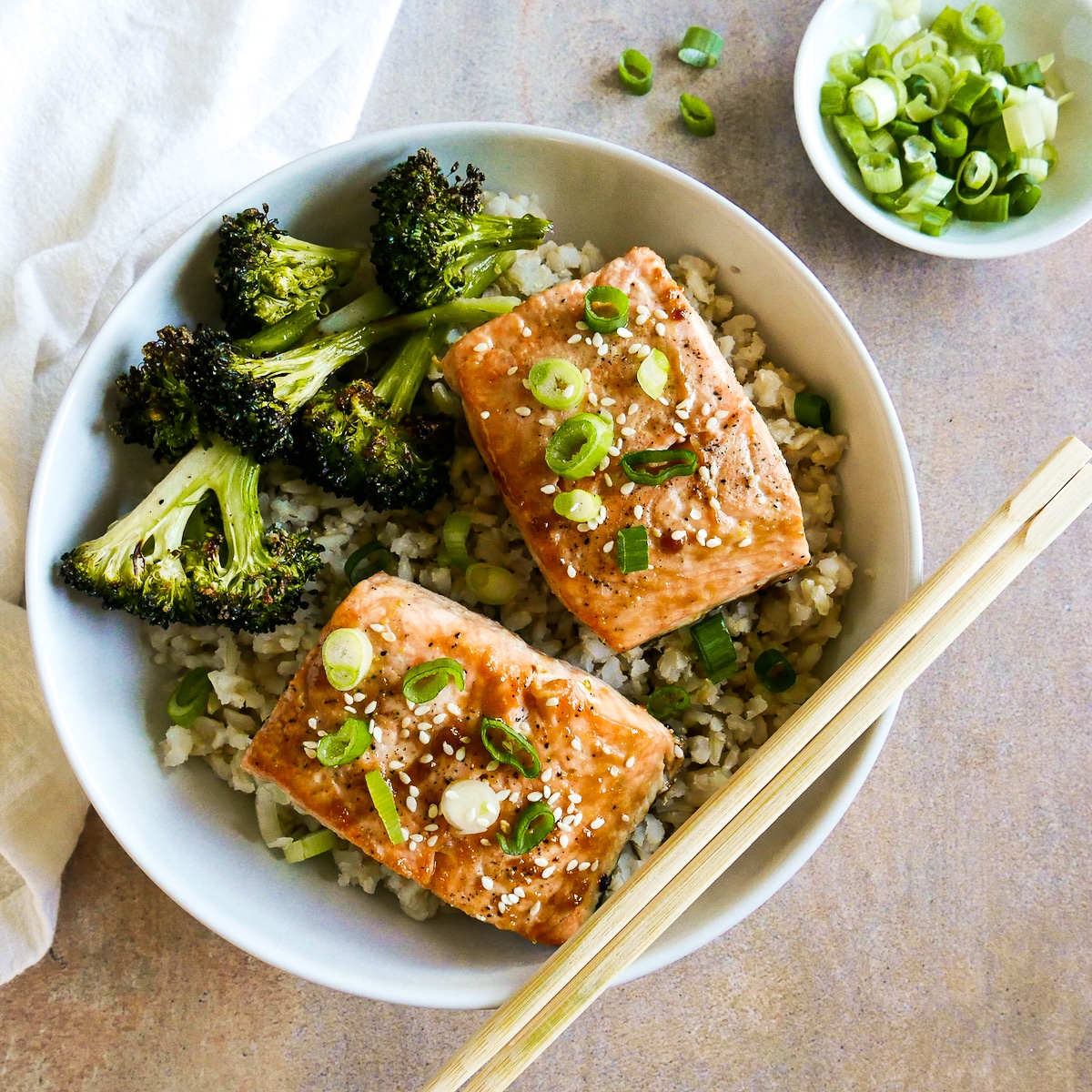 two pieces of salmon with miso butter and chopsticks in a bowl.
