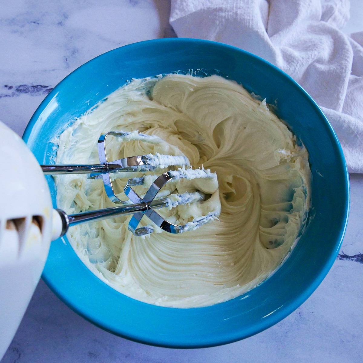 cream cheese, powdered sugar, and vanilla extract being mixed together.