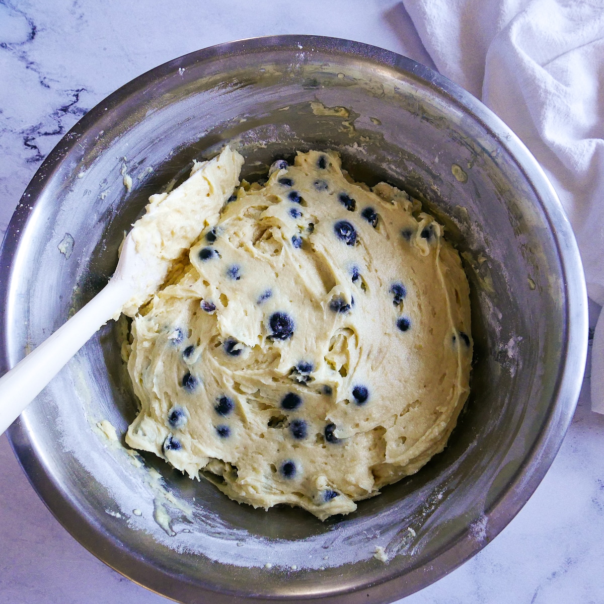 Blueberries folded into cake batter with a rubber spatula.