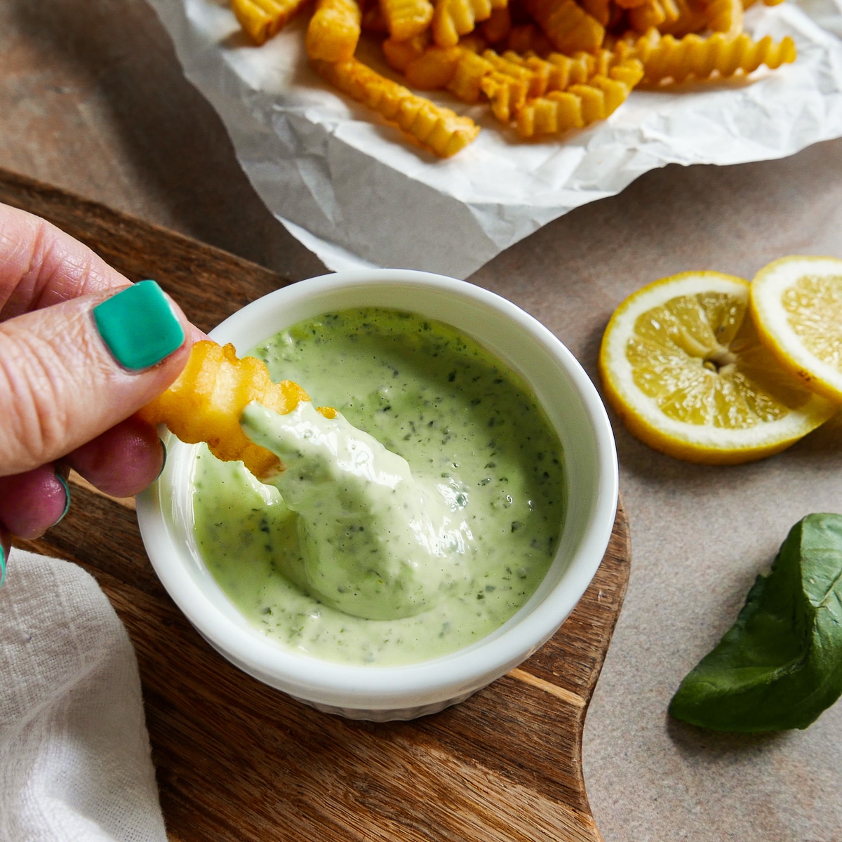french-fry-in-aioli.jpg White hand dipping french fry into a small cup of aioli.