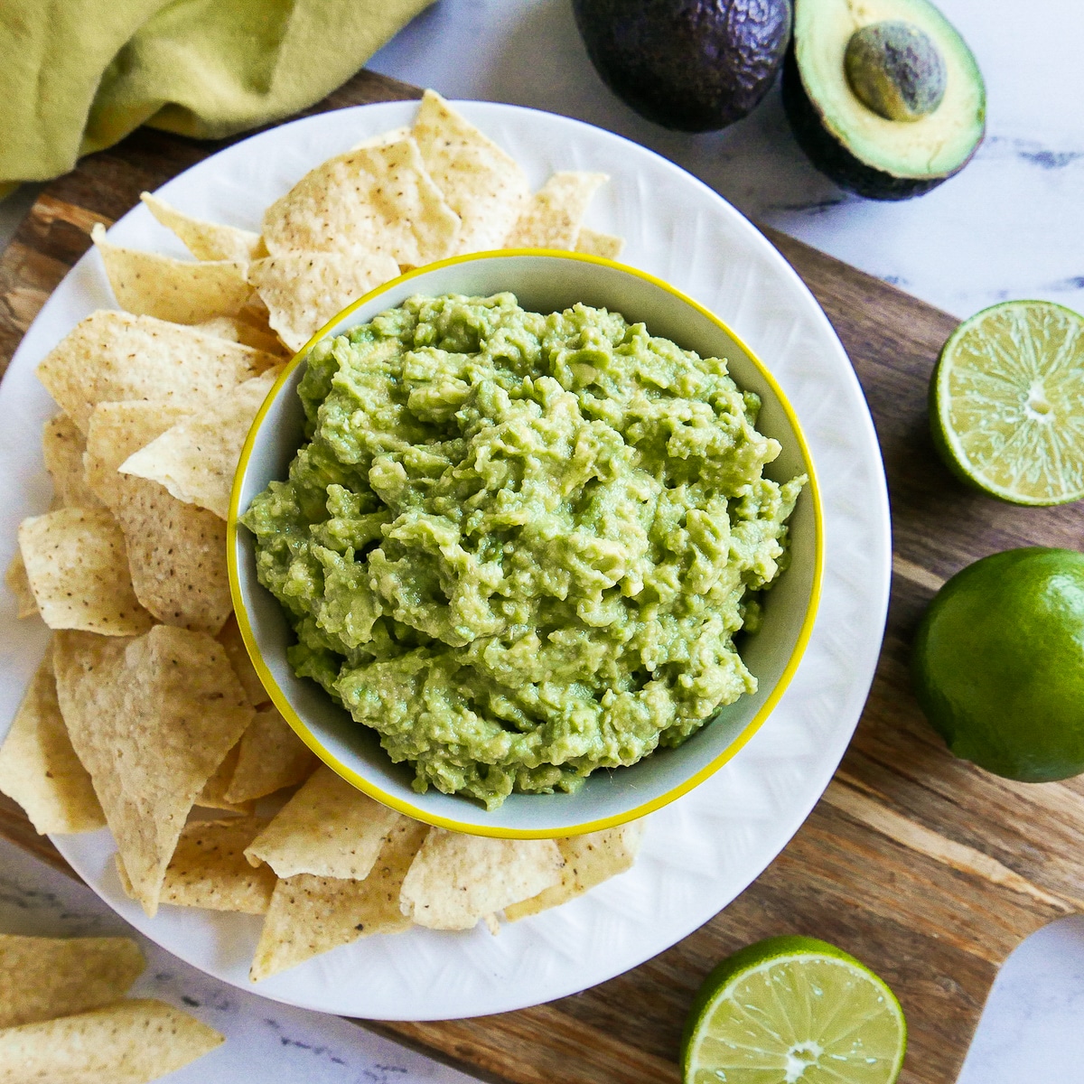 cup of easy guacamole with a plate of tortilla chips.