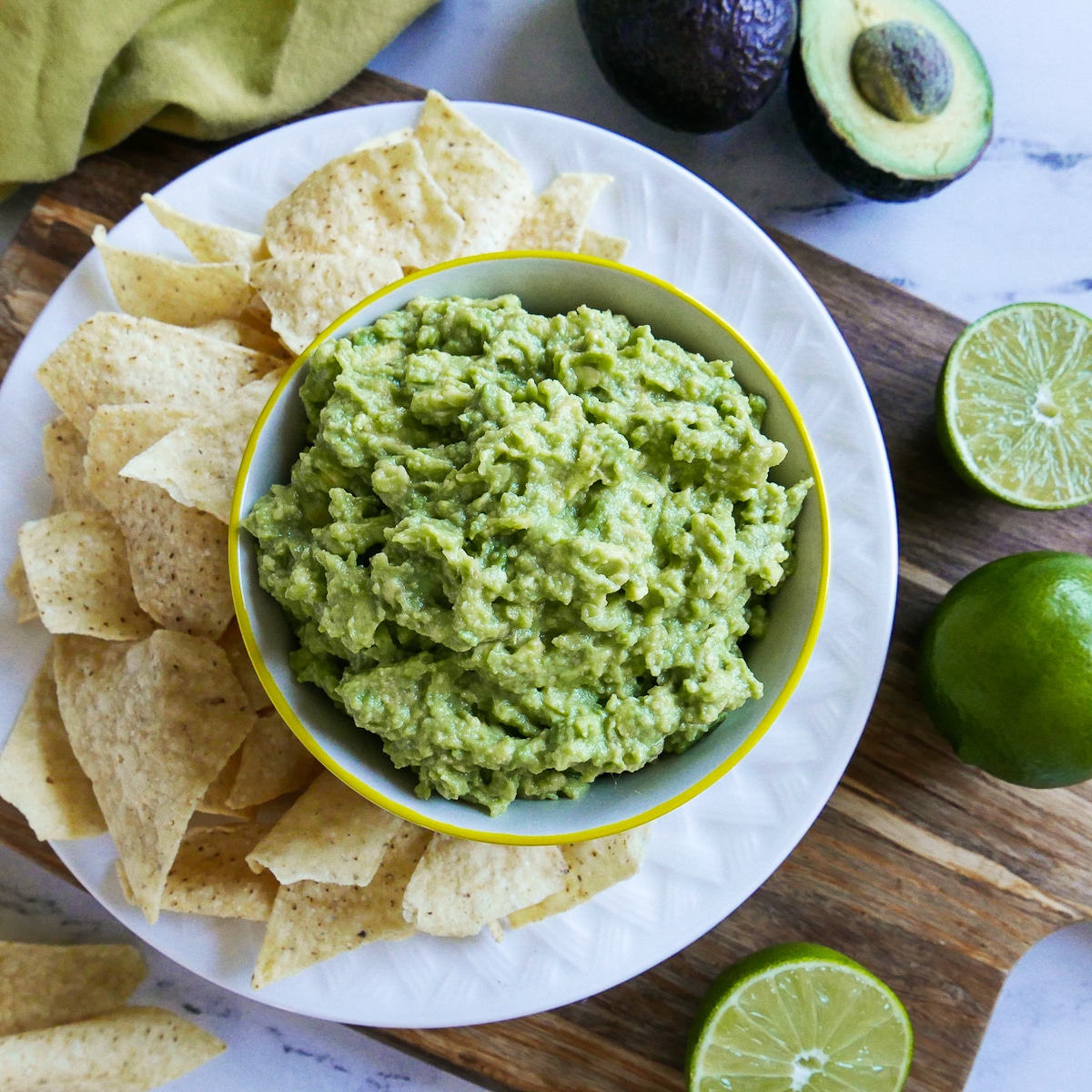 cup of easy guacamole with a plate of tortilla chips.
