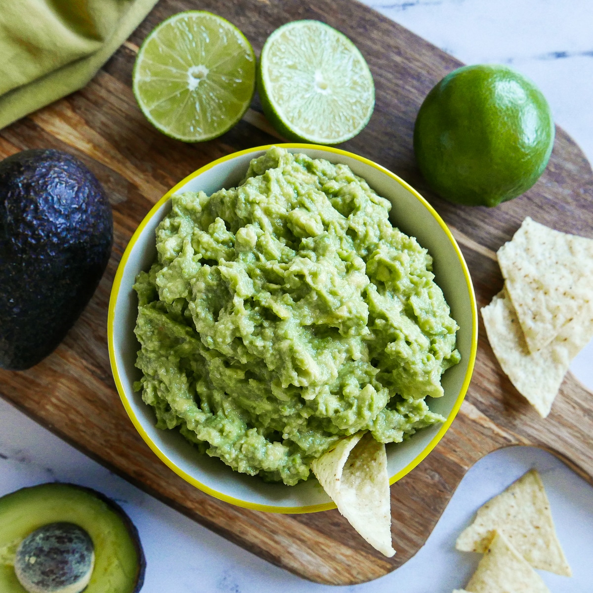 cup of simple guacamole with chips and lime on the side.