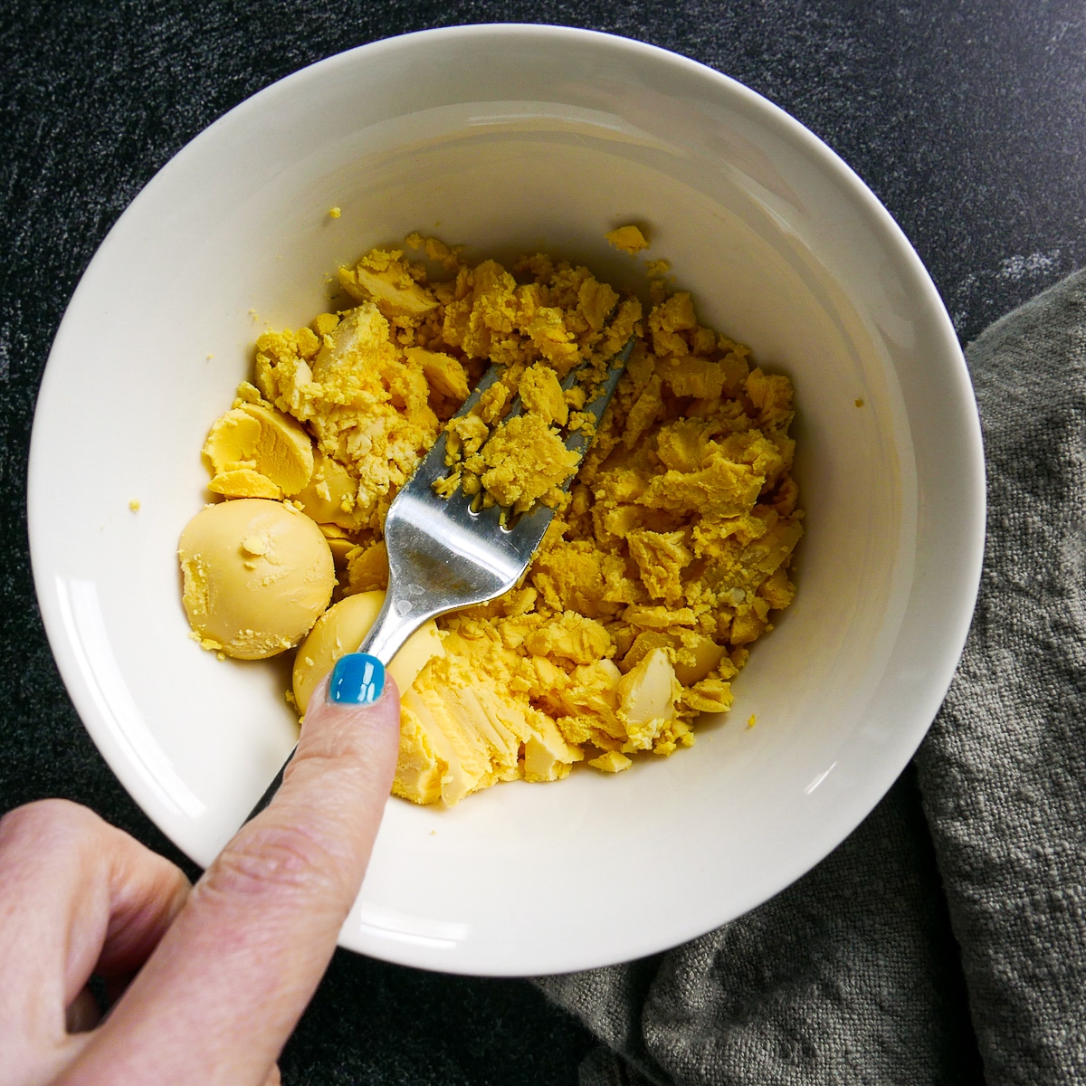 fork-mashing-egg-yolks.jpg fork mashing cooked egg yolks in a small bowl.