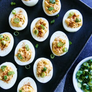 Spicy deviled eggs arranged on a black platter.