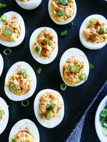 Spicy deviled eggs arranged on a black platter.