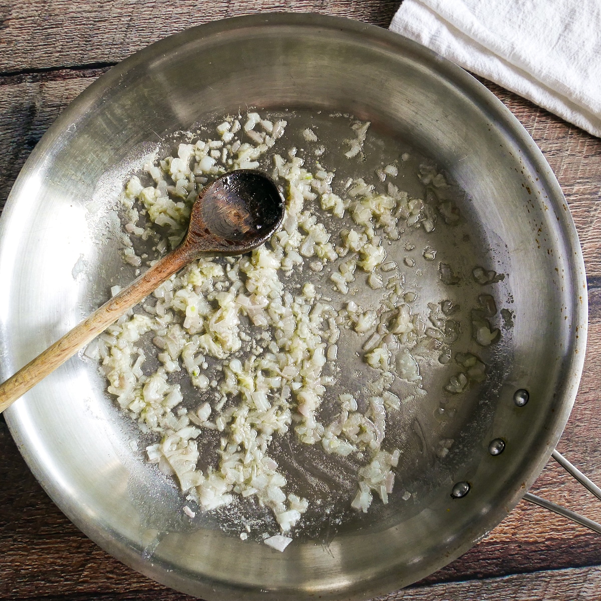 Diced shallots and minced garlic cooking in a large skillet.