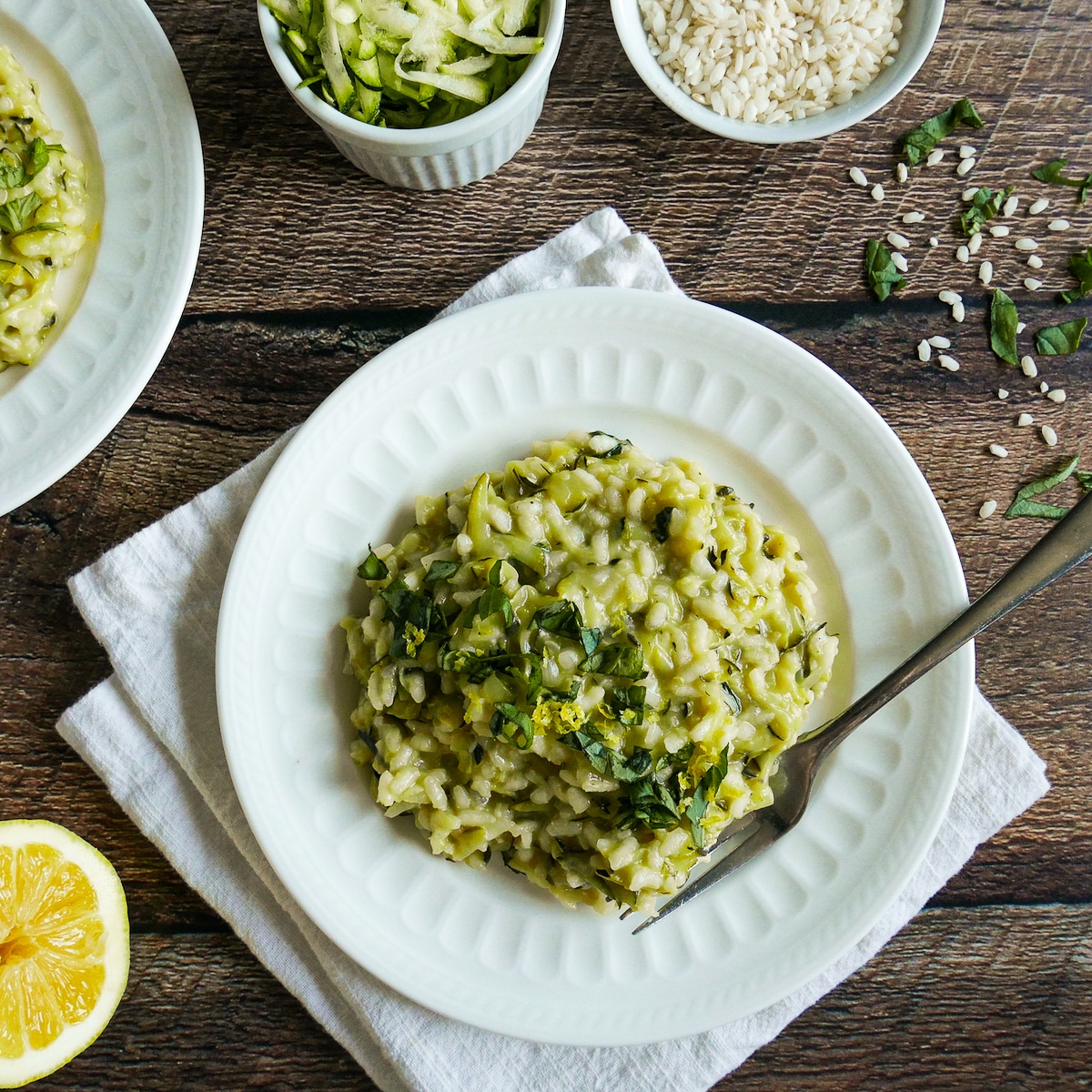 Summer squash risotto arranged on a white plate with a fork.