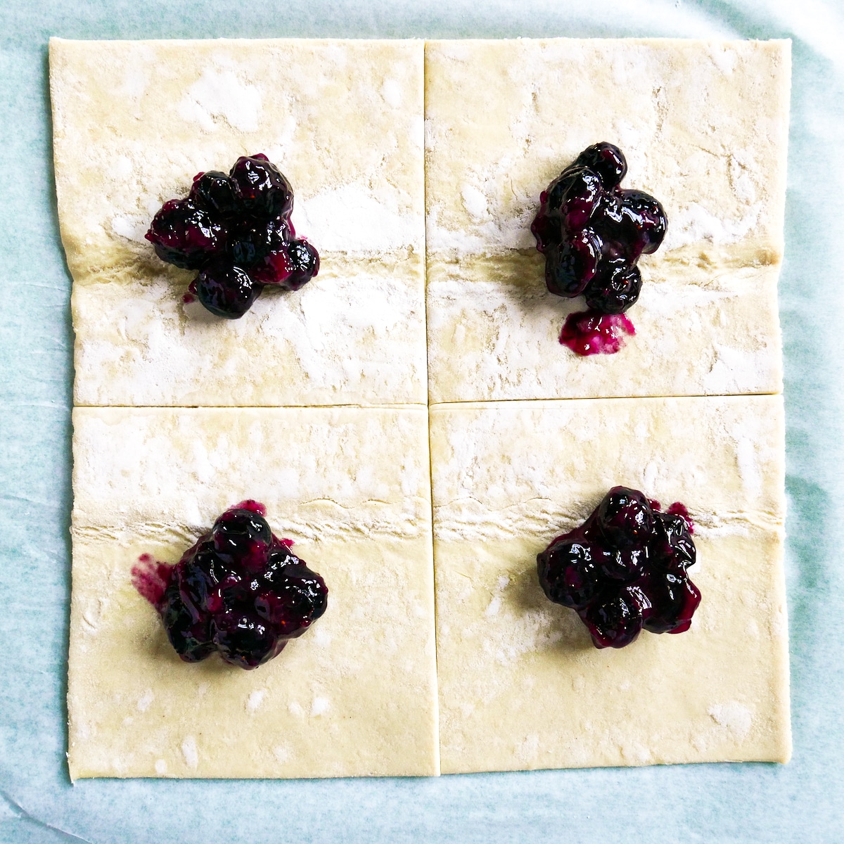 Blueberry filling added to center of puff pastry squares.