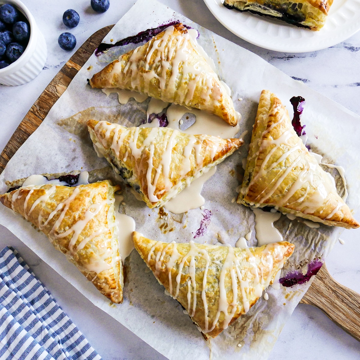 Glazed puff pastry turnovers arranged on parchment paper.