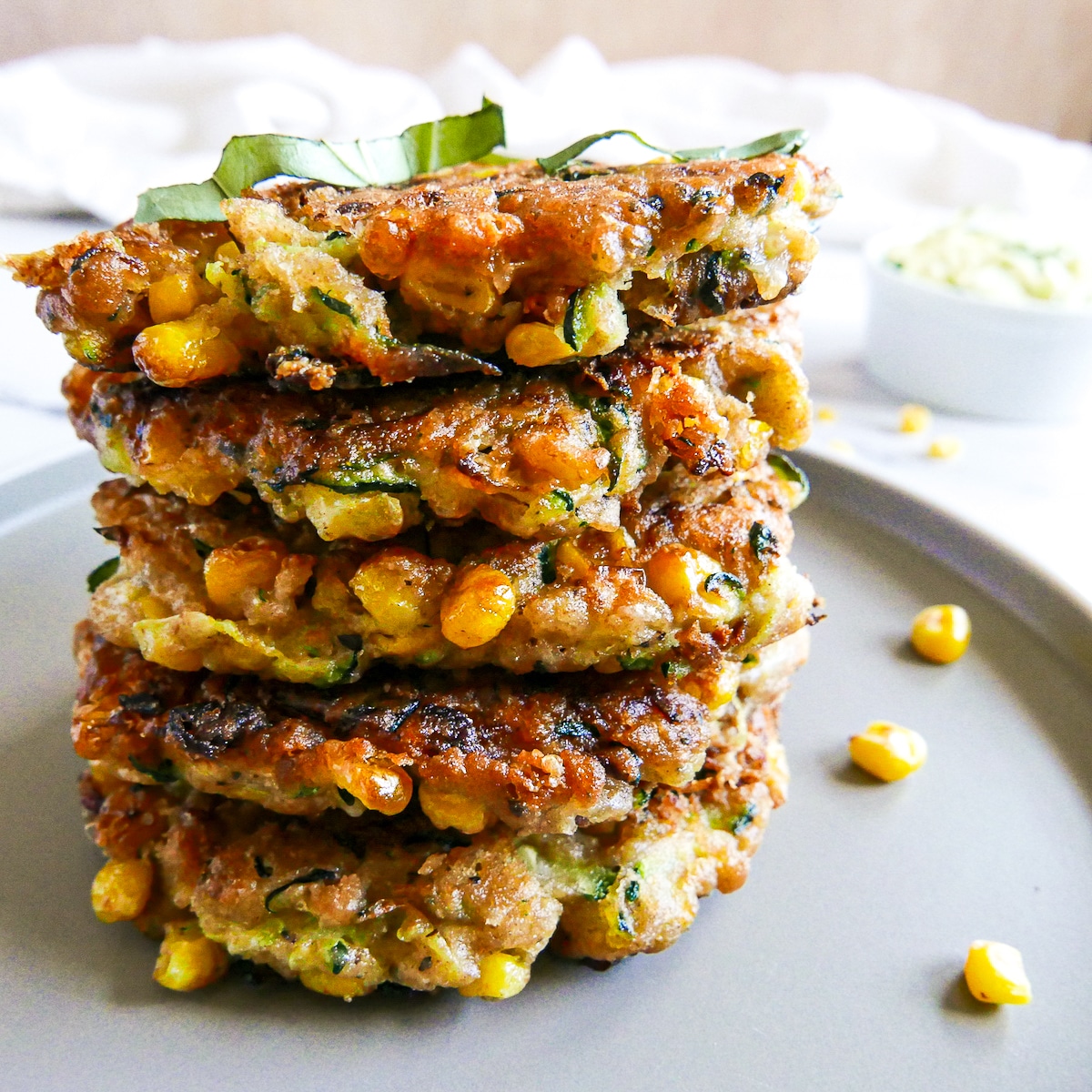 Stack of zucchini corn cakes on a small gray plate.