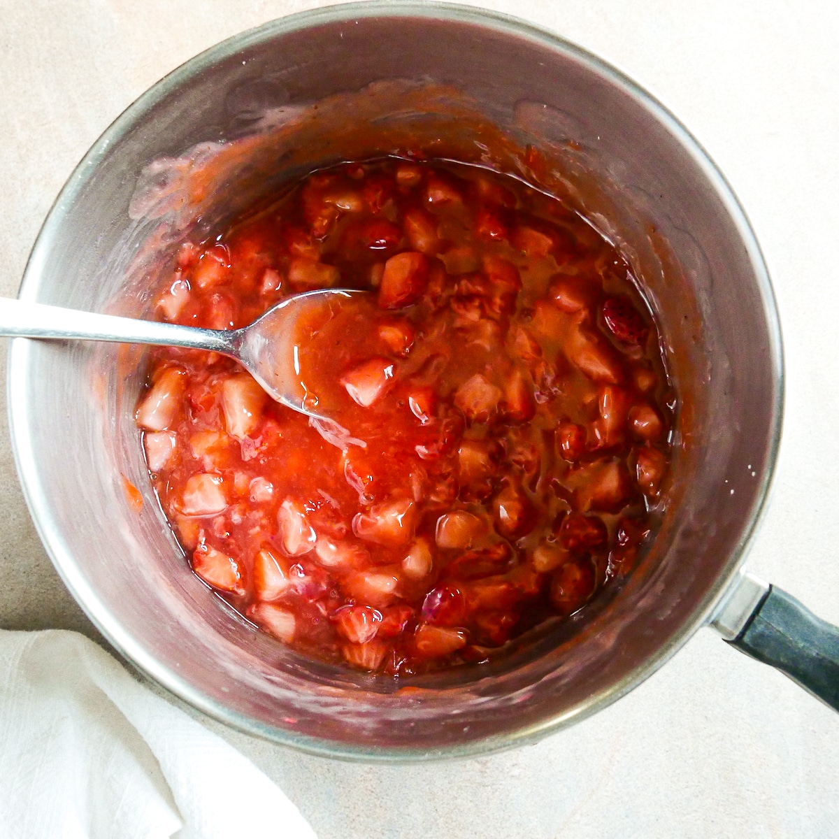 thickened-strawberry-filling.jpg Thickened strawberry filling with a spoon.