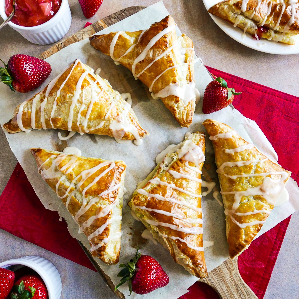 puff-pastry-turnovers.jpg Strawberry puff pastry arranged with strawberries on parchment paper.